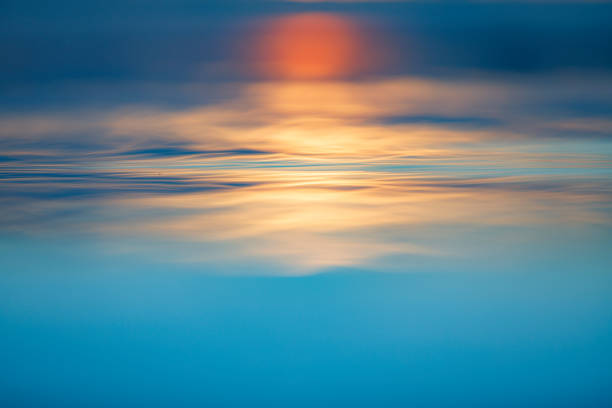 istock Long exposure reflection of sun on blue water surface 1392794200