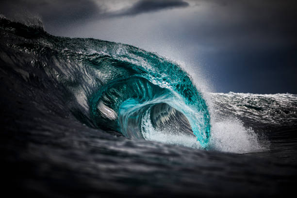 Dark and moody blue ocean wave crashing into sea