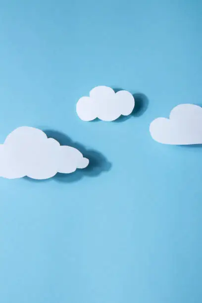 Paper art. White clouds on a bright blue background