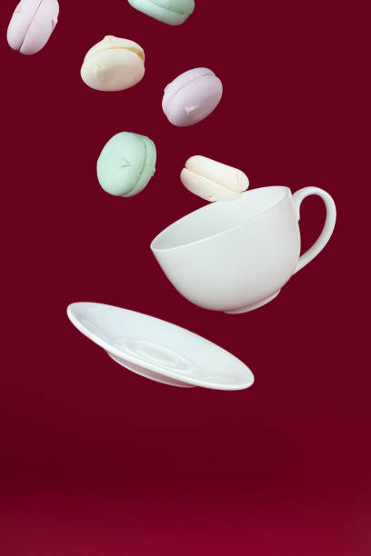 istock Porcelain cup and saucer flying with marshmallows on a red background. 1392794560