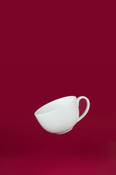 istock Flying Porcelain Cup with on red background. Porcelain white coffee cup mug. 1392794562