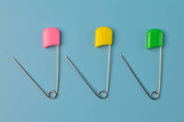 istock Safety pins isolated on a blue background 1392794996
