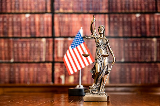 Lessons for the future for Law or human rights after the epidemic. Statue of justice in front of law books and USA Flag