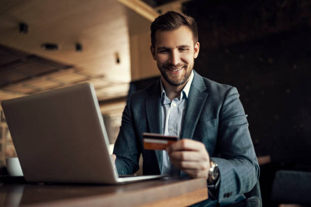 istock Businessman holding credit card while online shopping using laptop 1392798277