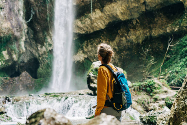 istock Athletic active hiking woman with a backpack exploring a waterfall in a canyon. 1392799412
