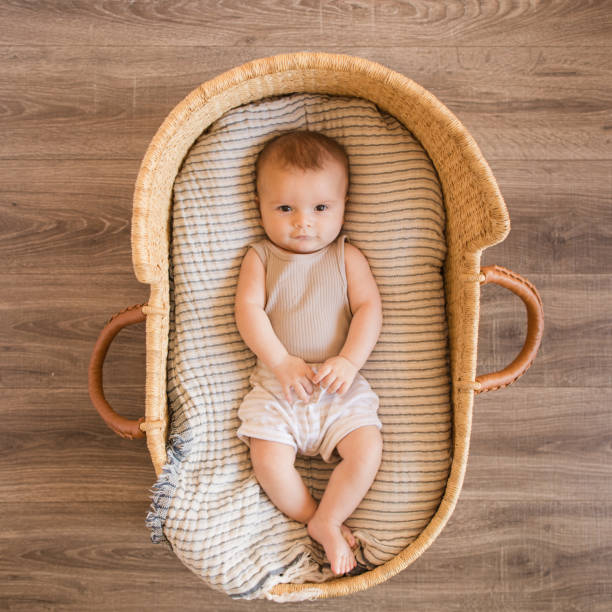 A 17 Week Old Baby Boy Looking Up While Laying in a Cozy Cream Cotton Blanket in a Seagrass Moses Basket A 17 Week Old Baby Boy Looking Up While Laying in a Cozy Cream Cotton Blanket in a Seagrass Moses Basket gender neutral photos stock pictures, royalty-free photos & images