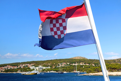 Flag of Croatia on a boat, blowing in the wind. Town Hvar on island Hvar is in the background. Selective focus.