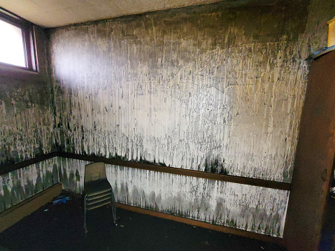 A fire damaged wall with chairs sitting in the corner