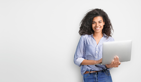 Portrait of a beautiful african woman with laptop on grey backround. Copy space