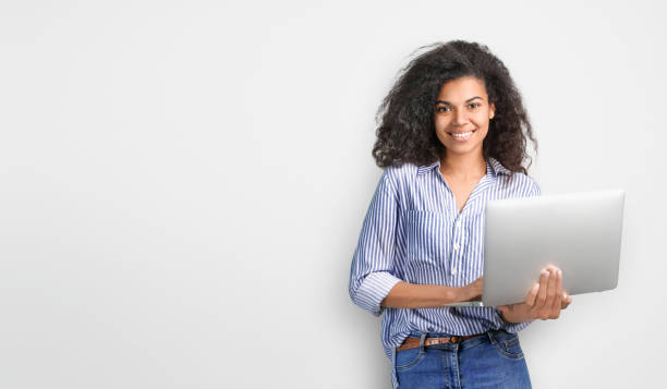 Portrait of a beautiful african woman with laptop on grey backround. Copy space Portrait of a beautiful african woman with laptop on grey backround. Copy space Holding stock pictures, royalty-free photos & images