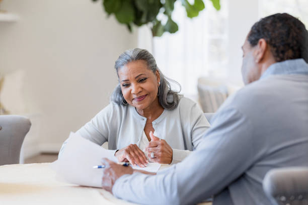 istock Senior woman reads document male lawyer shows her 1392802400