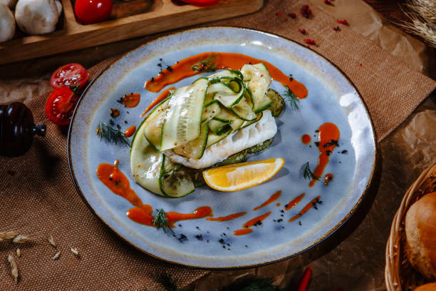 istock Boiled fish covered with fresh cucumber on a plate. Top view 1392803503