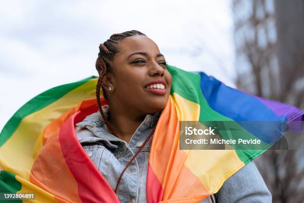 Confident Black Woman Outdoors Holding A Rainbow Flag Stock Photo - Download Image Now