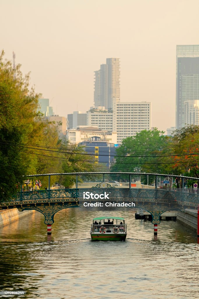Cityscape of Krung Thep Maha Nakhon (Bangkok), Thailand with electric passenger boat sailing at Phadung Krung Kasem canal on evening time on downtown background Architecture Stock Photo