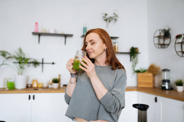 istock a red-haired woman prepares a green smoothie 1392806545