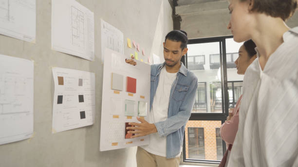 istock A group of multi ethnic business designer team talk, communicate, discuss, and work in meeting room on construction site, present ideas to colleagues. People lifestyle. Corporation 1392806729