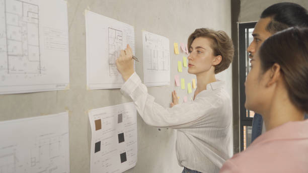 istock A group of multi ethnic business designer team talk, communicate, discuss, and work in meeting room on construction site, present ideas to colleagues. People lifestyle. Corporation 1392806741