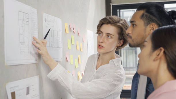 istock A group of multi ethnic business designer team talk, communicate, discuss, and work in meeting room on construction site, present ideas to colleagues. People lifestyle. Corporation 1392806747