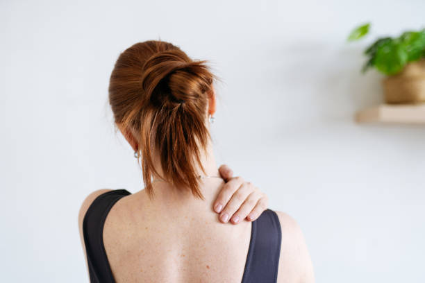 istock a red-haired woman kneads her shoulder. view from the back 1392807411