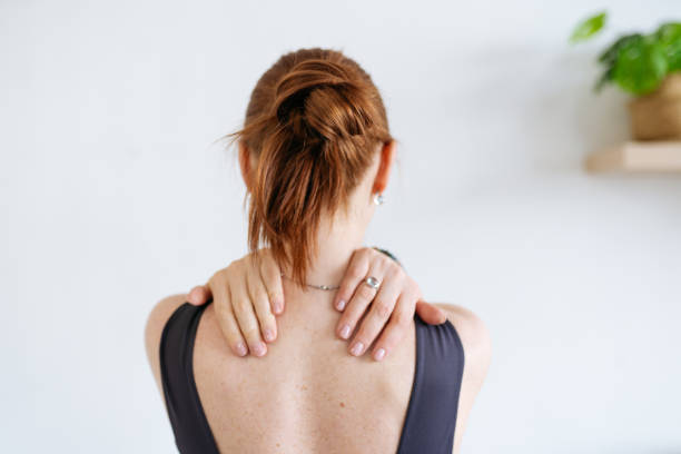istock a red-haired woman kneads her shoulders. view from the back 1392807412