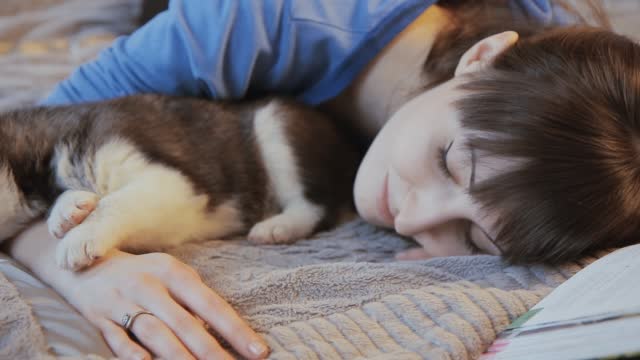 girl lying with puppy Siberian husky on the bed and smiling,dolly