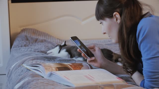 girl on the bed with the phone, the Siberian Husky puppy sleeping beside her,dolly,slider