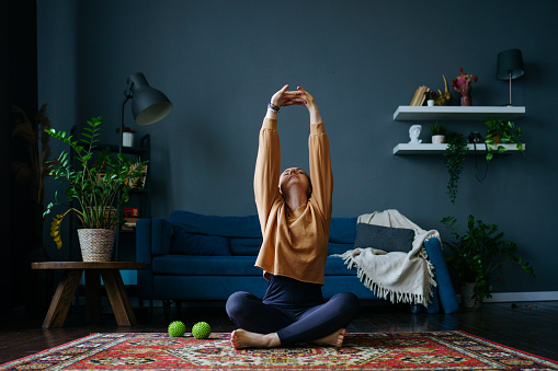 a red-haired woman in a tracksuit does exercises in the living room