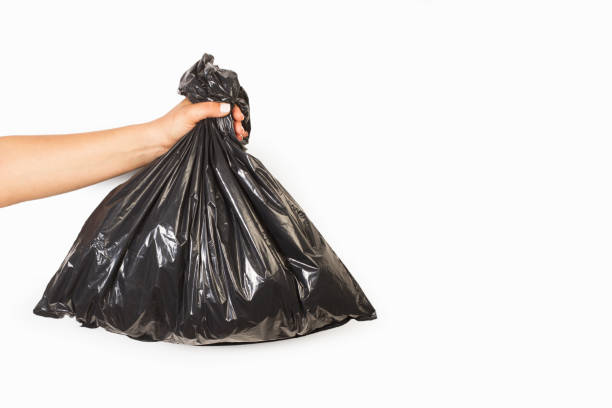 istock Woman hand holding a black plastic bag on a white background 1392807980