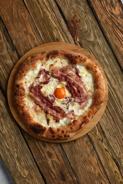 istock Carbonara pizza with bacon and egg on wooden background 1392808233