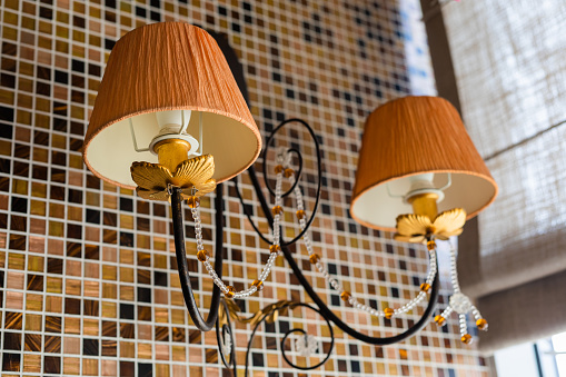 Two-lamp sconce with two fabric orange lampshades. Classic wall lamp in restaurant