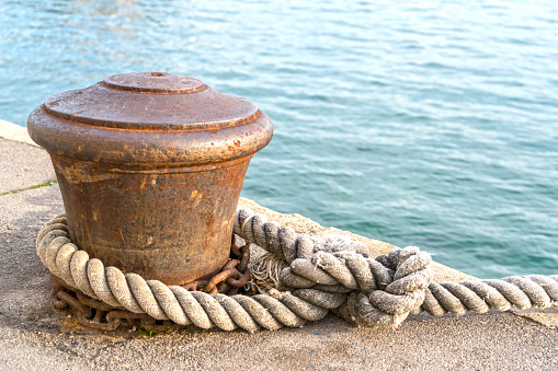 Close up of mooring rope to the iron grip on the pier at the sea