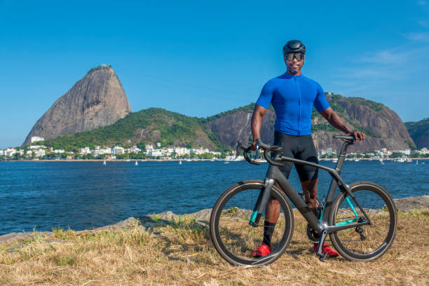 athlet posiert mit seinem fahrrad mit dem zuckerhut im hintergrund - brazil bicycle rio de janeiro outdoors stock-fotos und bilder