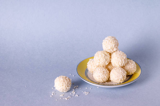 sweets in coconut flakes on a blue background, copy space