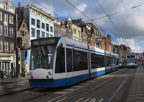 Amsterdam, the Netherlands - April 20, 2011: Two trams and a group of travellers in front of Amsterdam Central railway station. The local government discourages to drive a car in the Amsterdam city center, making public transport (tram, metro, bus) very important. In total there are 16 tramlines.
