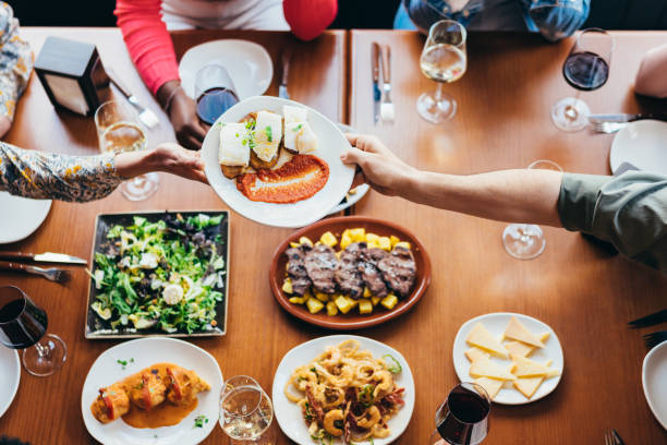 istock a white woman receives a plate of codfish from another diner while several friends are eating 1392831652