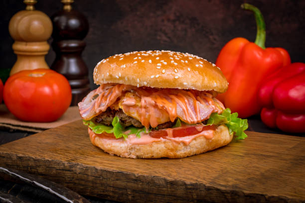 istock Burger with meat patty, cheese and bacon on board 1392831657