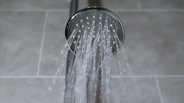 Turning on the shower, the flow of water from the shower head in the bathroom. Chrome plated watering can