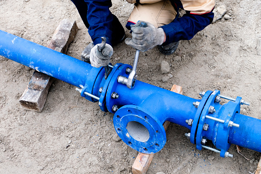 Workers installing water supply pipeline system, close up.