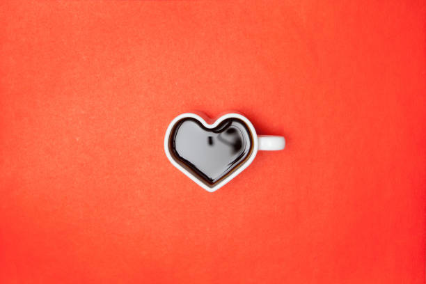 Heart shape coffee cups over red background. View from above. Flat lay.