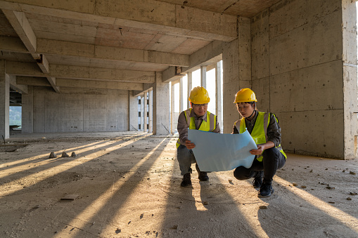 Male and female construction engineers with drawings comparing data