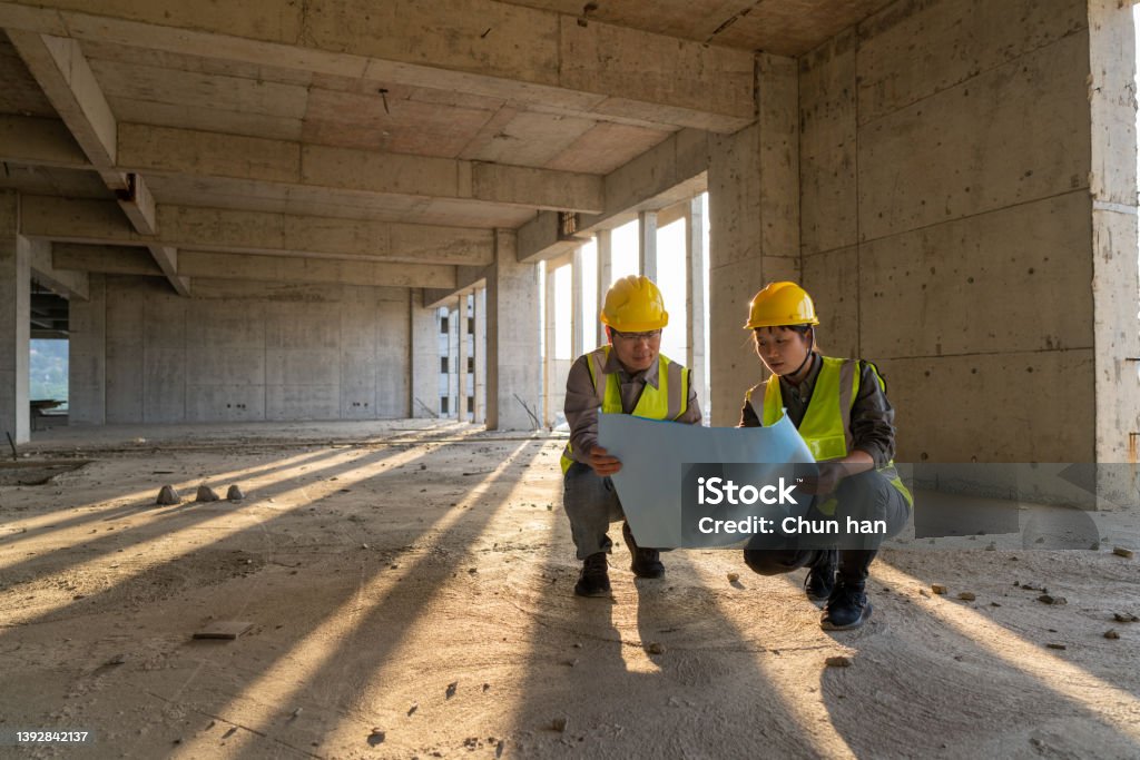 Male and female construction engineers with drawings comparing data Construction Industry Stock Photo