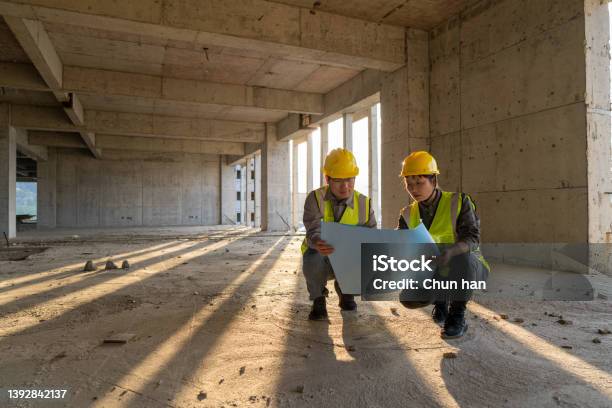 Male And Female Construction Engineers With Drawings Comparing Data Stock Photo - Download Image Now
