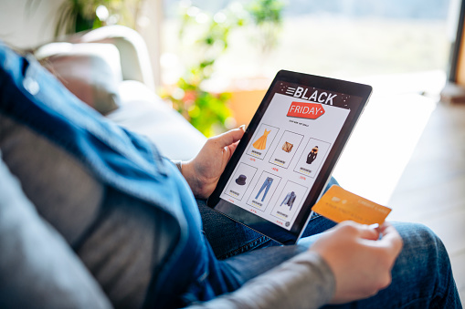 Pregnant woman using digital tablet to shop from Black Friday sale at home.