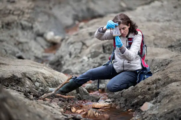 Biologist Examining Sedimentation of Water on Location of Almost Dried Riverbed Using Laboratory Glassware