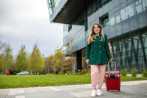 istock Young woman pulling suitcase while going to business travel 1392851097
