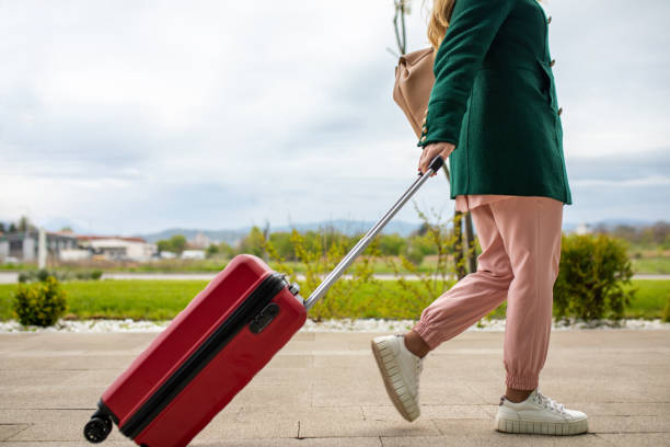 istock Young woman pulling suitcase while going to business travel 1392851126