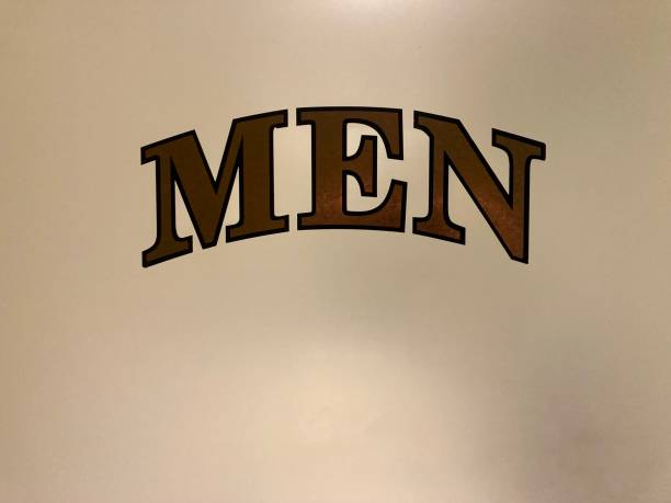 Semi translucent glass on a men’s bathroom door displaying the title, backlit.