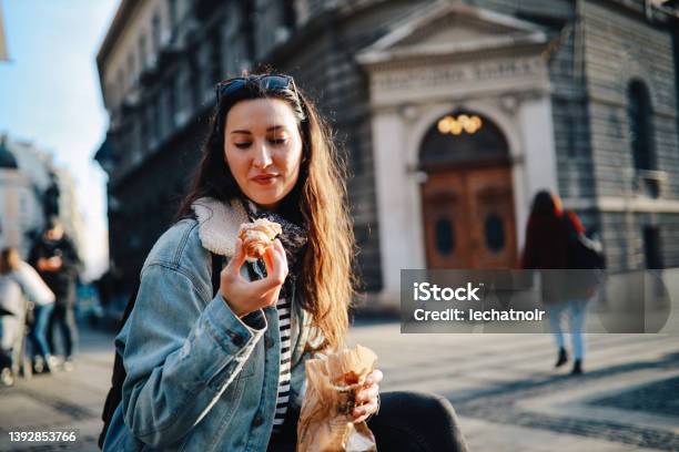 Young Woman Eating A Croissant On The Street Stock Photo - Download Image Now - Croissant, Coffee - Drink, Adult