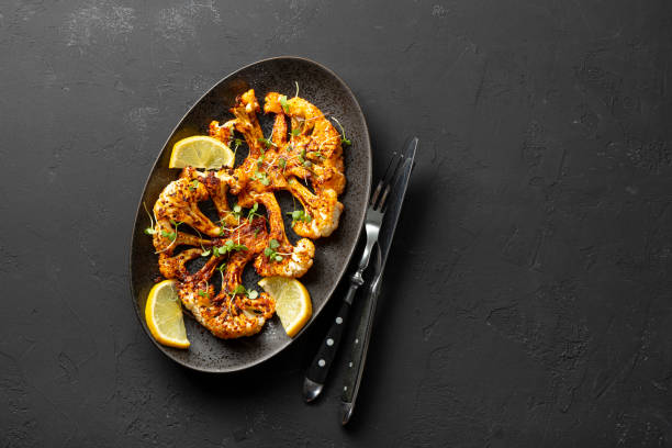 istock Vegetarian cauliflower steaks with microgreens and lemon on the black background, top view copy space for text. Alternative to traditional meat steaks for vegans. 1392854682
