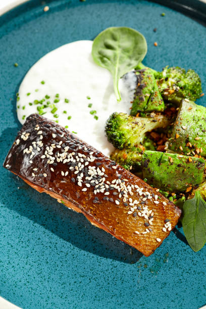 salmone arrosto con buccia croccante, verdure grigliate ed espuma. filetto di salmone alla griglia con broccoli, avocado e salsa bianca. keto food - pesce al forno con pelle e verdure verdi su sfondo bianco. - salmone arrosto foto e immagini stock